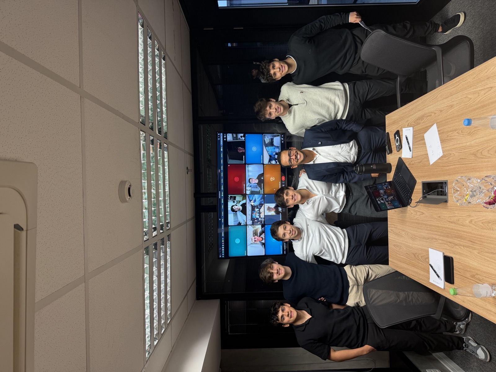 Jovens da primeira turma da formação ALTA em uma sala de reunião premium, ao lado de um mentor